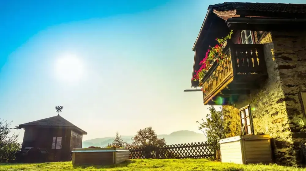 Haus mit blühendem Balkon und Hochbeet im Garten in der Abendsonne