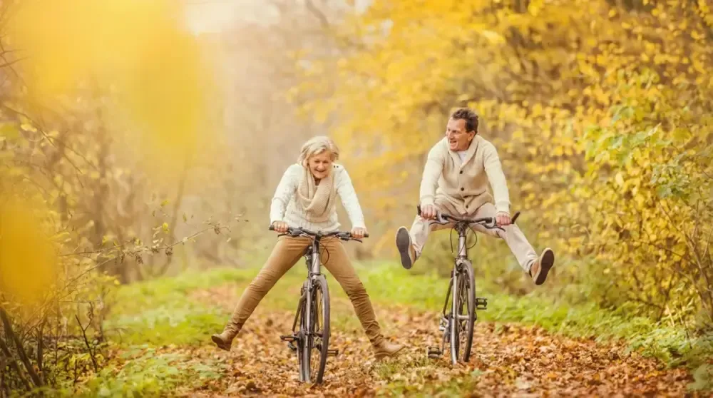 Aktives älteres Paar fährt ausgelassen Fahrrad im herbstlichen Wald